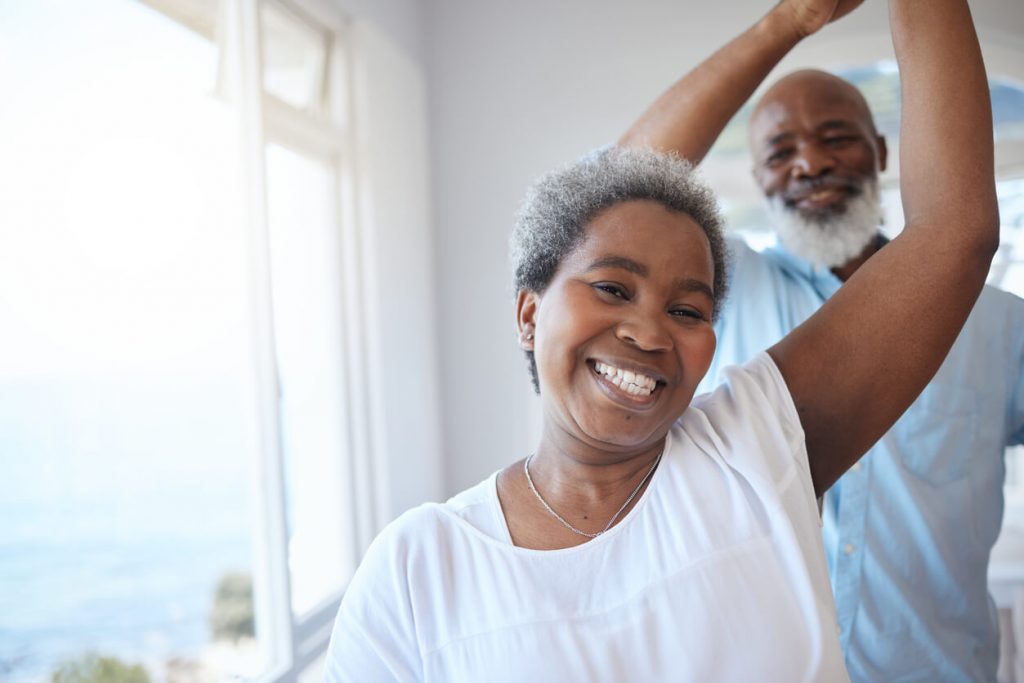 Mature couple dancing inside their apartment.