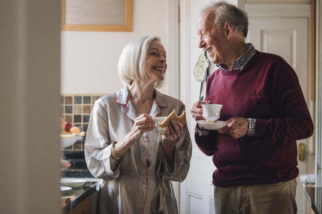 A happy older couple smiling in the kitchen.