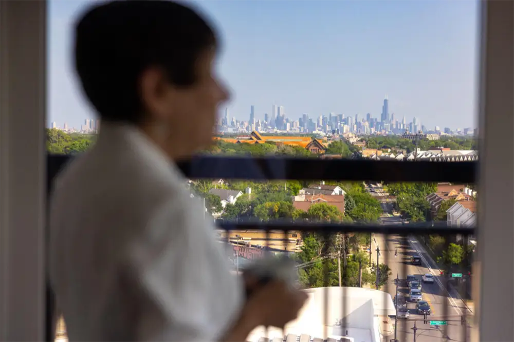 Elderly woman drinking coffee enjoying the view of the city from a balcony