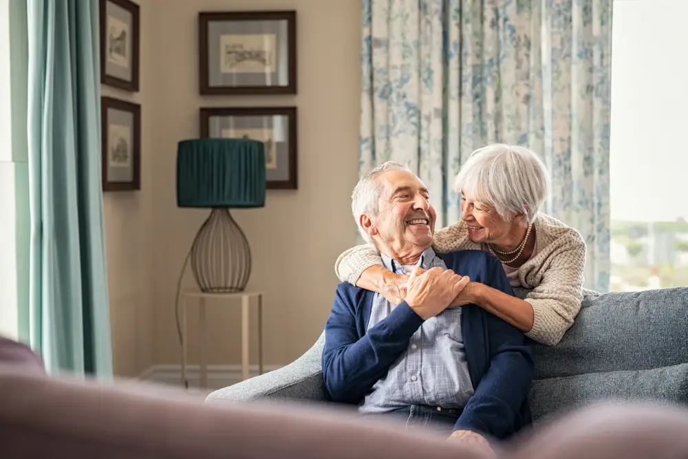 a senior woman wrapping her arms around her smiling husband