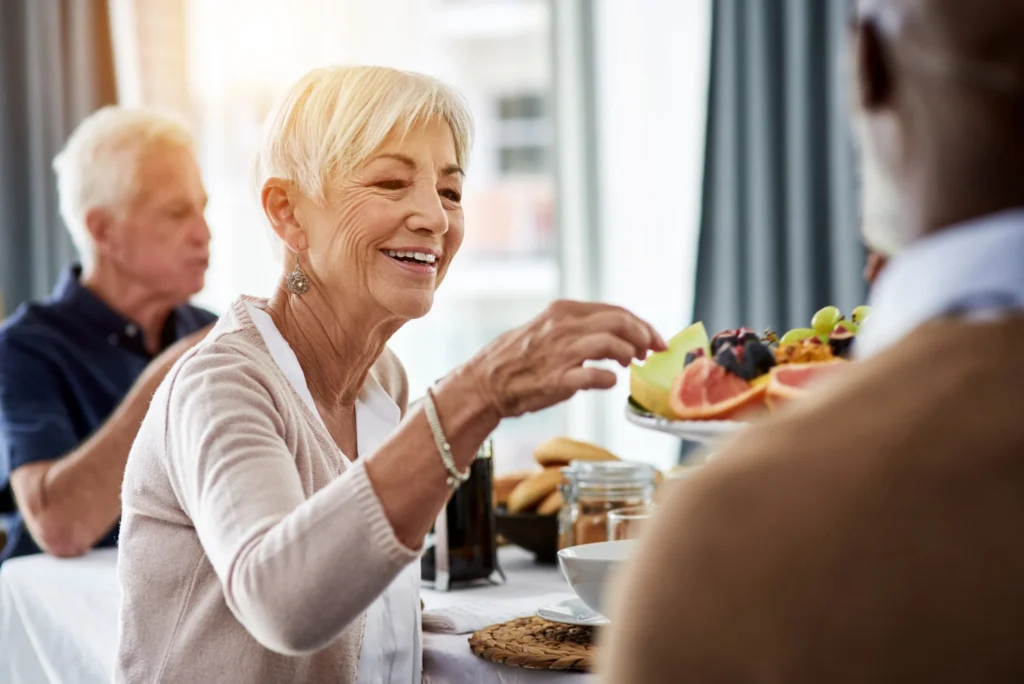 senior woman selecting fruit from plate because she knows the foods to avoid with Parkinson's disease